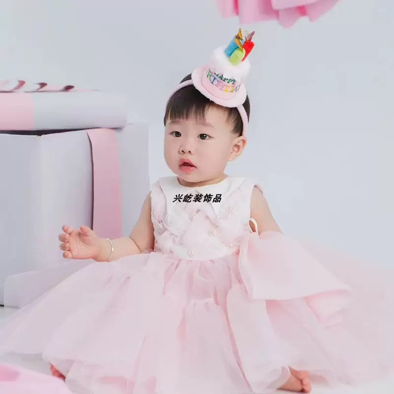 Baby girl wearing pink happy birthday cake headband for 1st birthday photoshoot