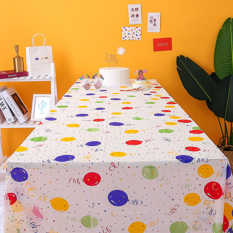 Happy birthday balloon print tablecloth on party table with cake setup