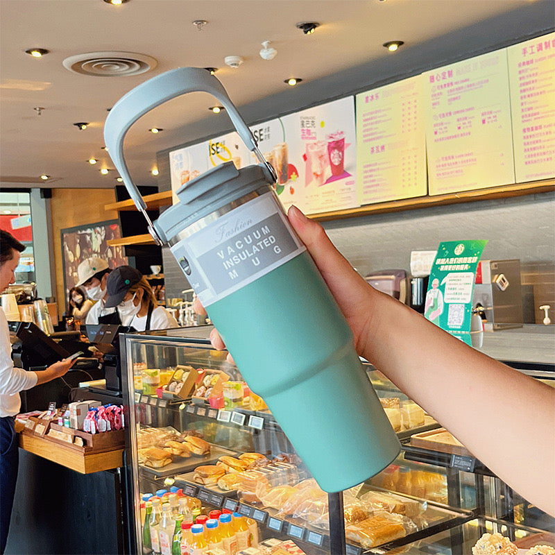 Stylish green stainless steel tumbler in coffee shop setting – reusable and leakproof